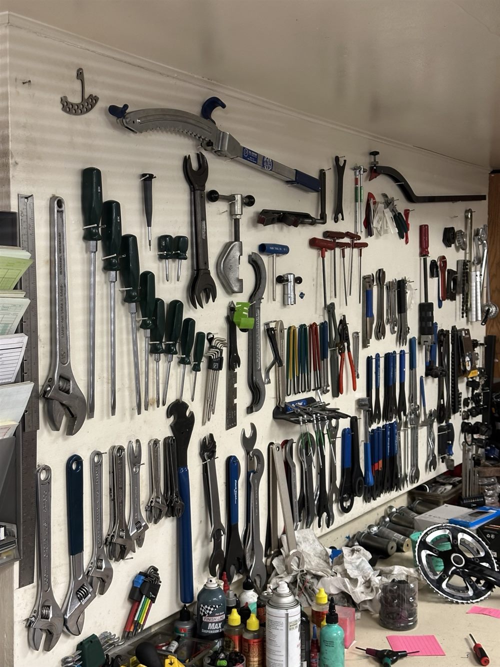 Bicycle service tools arranged on the wall above the Bicycles Plus workshop bench